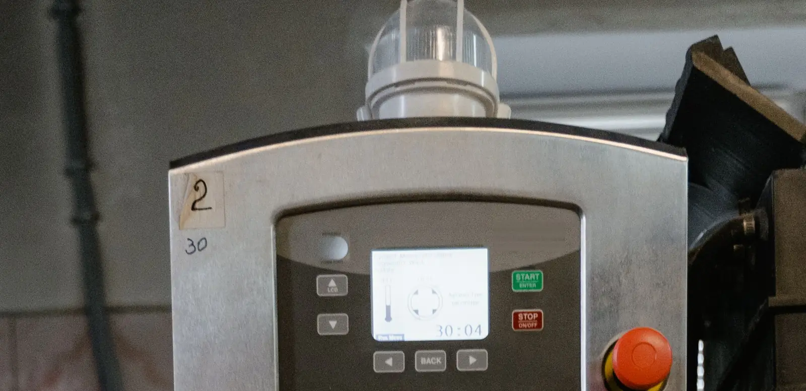 Programmable washer-extractor controller with a display, start and stop keys, and an emergency stop button