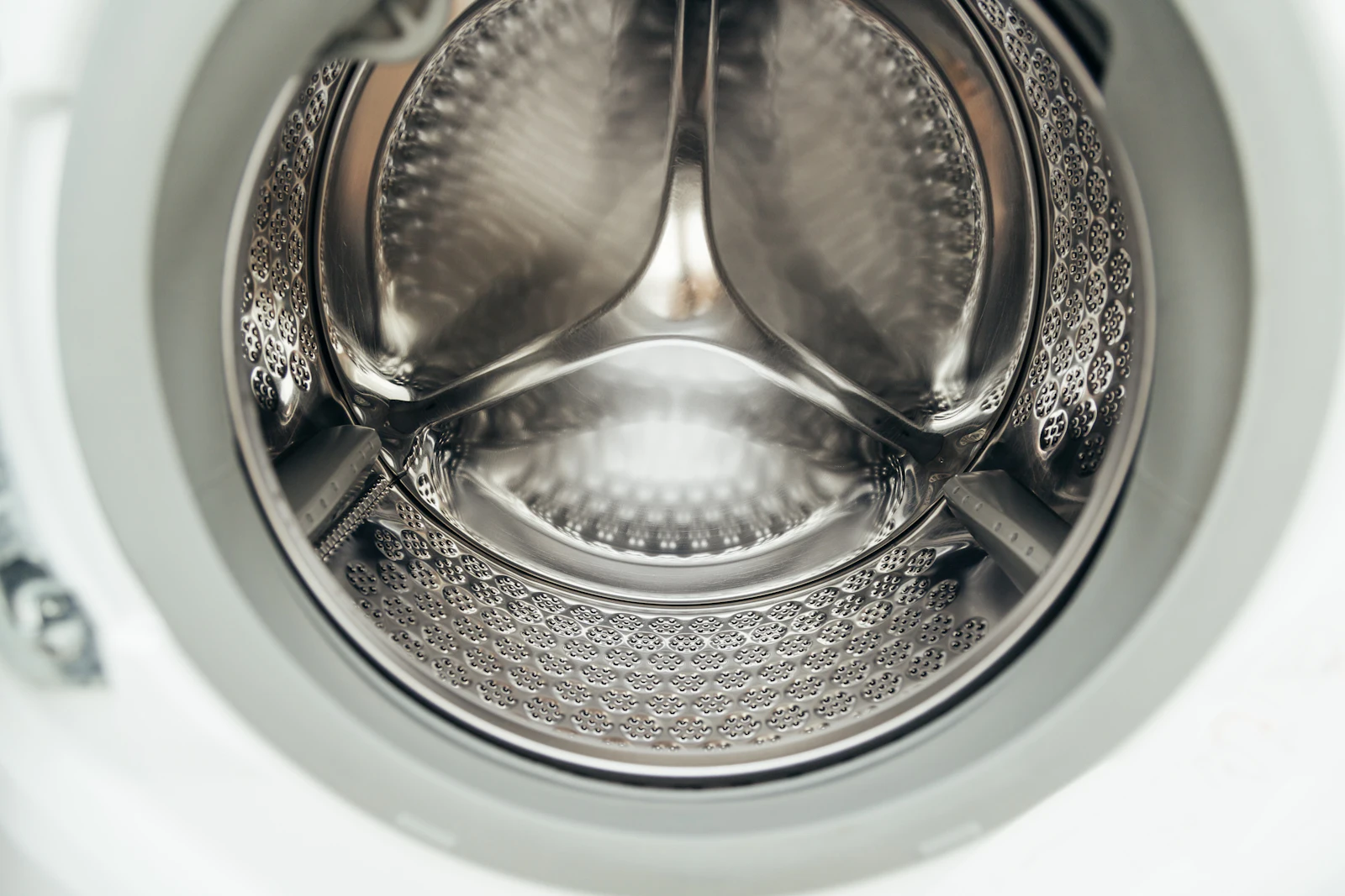 Inside of an empty stainless washer drum seen through the door opening