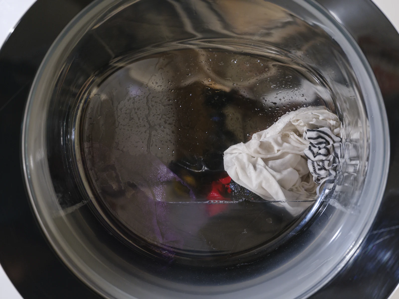 Water and laundry seen through the glass door of a washer