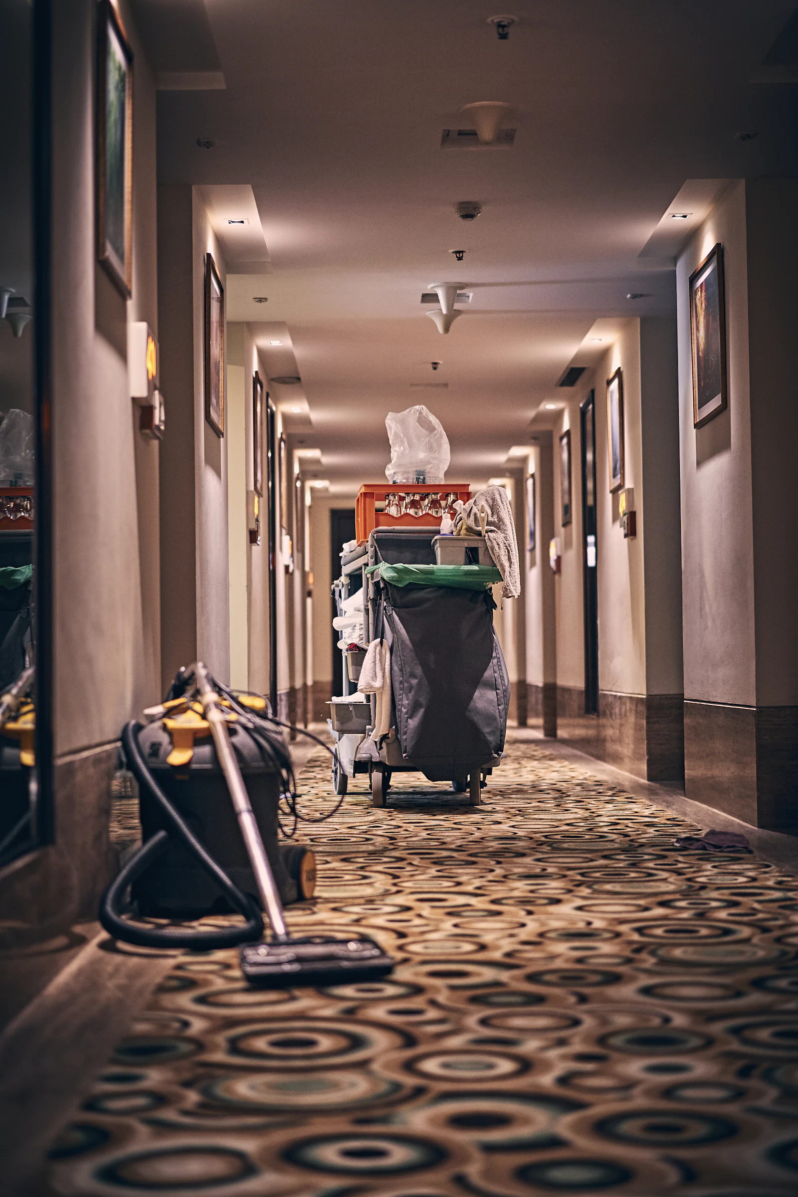 Housekeeping cart and vacuum in a long hotel corridor