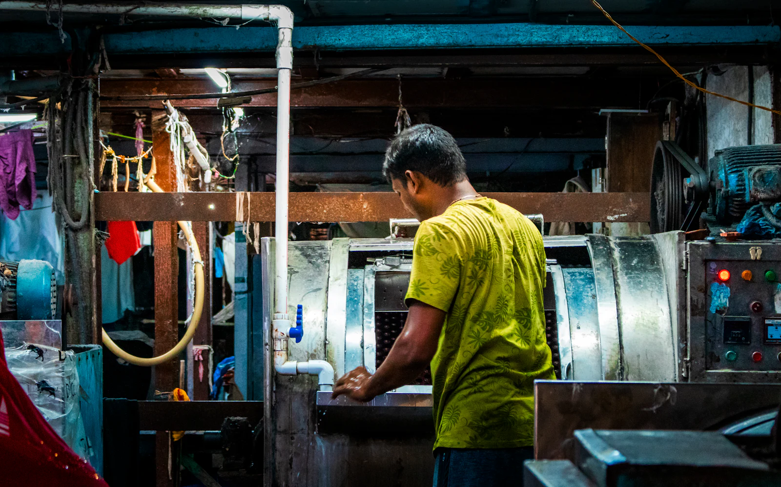 Worker at a large open-pocket washer in an industrial laundry
