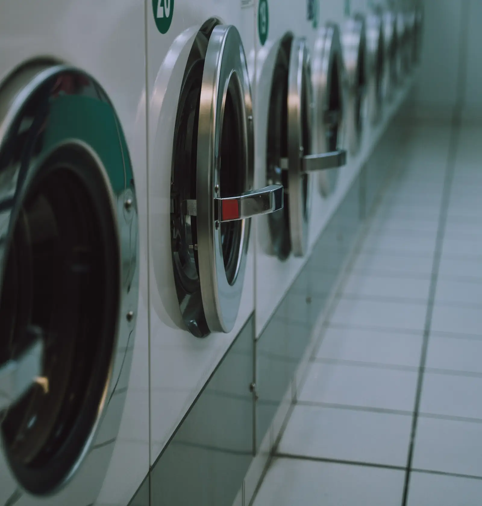 Row of front-load washers along a tiled laundromat floor