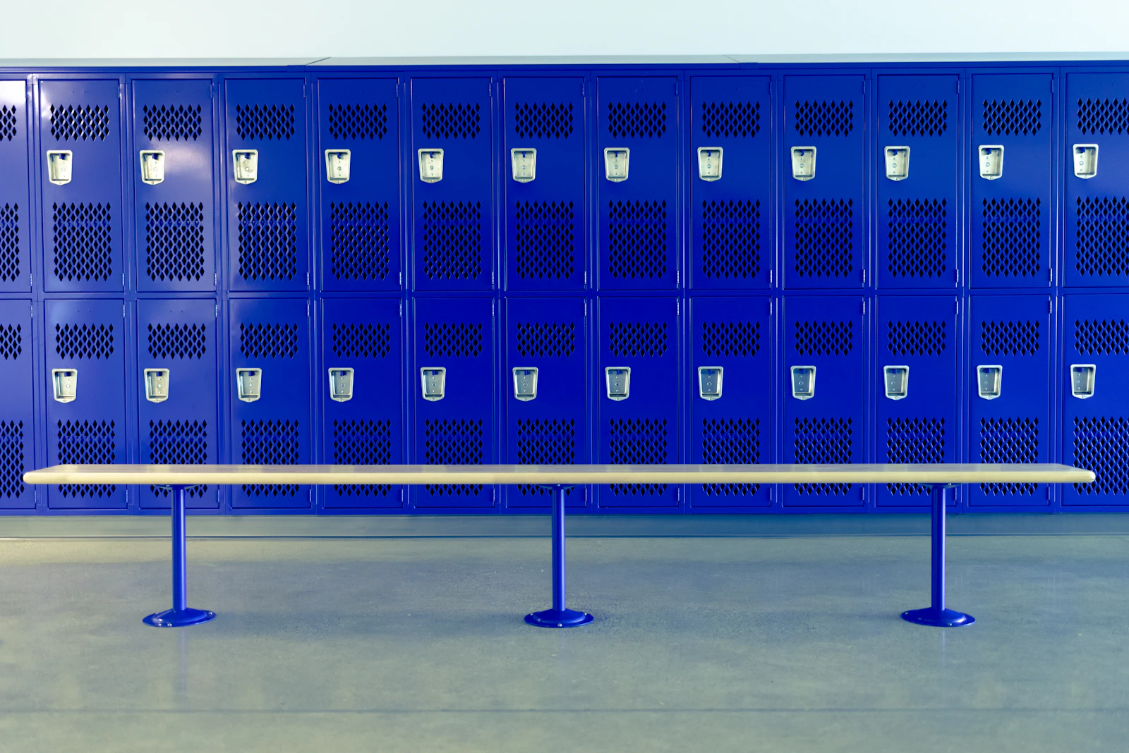 Blue lockers and a bench in an athletic locker room