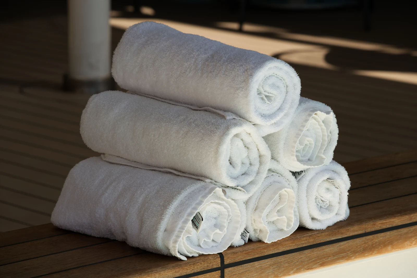 Rolled white towels stacked on a wooden bench