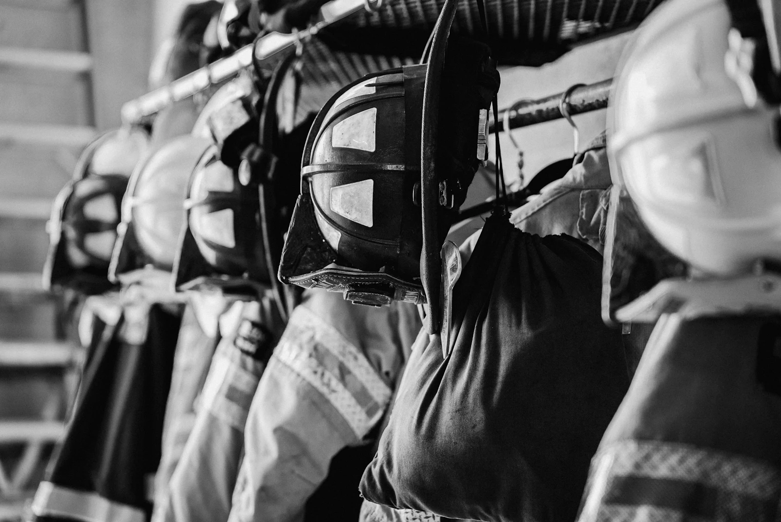 Helmets and turnout gear on a rack, in black and white